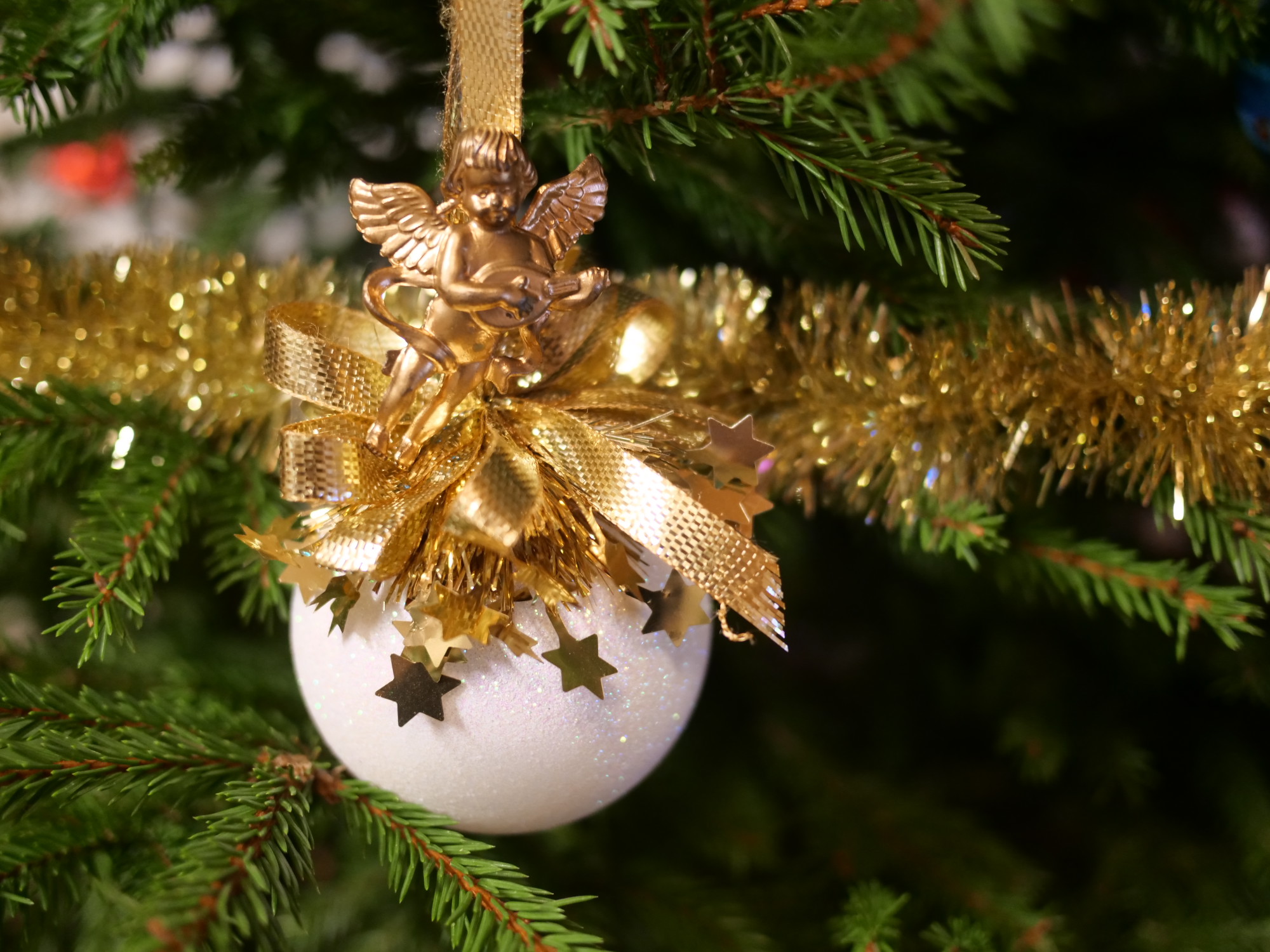 iso valkoinen joulupallo, jossa on kultaisia koristeita.