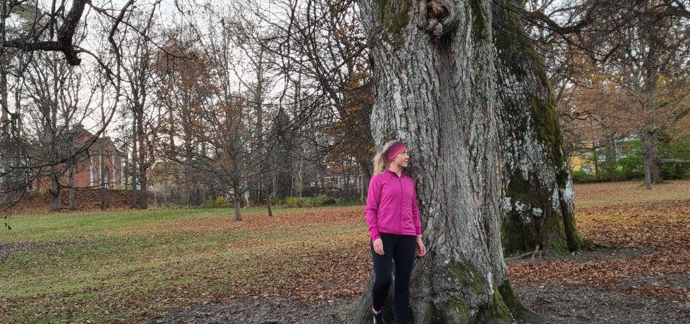 juoksija nojaa isoon vanhaan puuhun traskandan puistossa