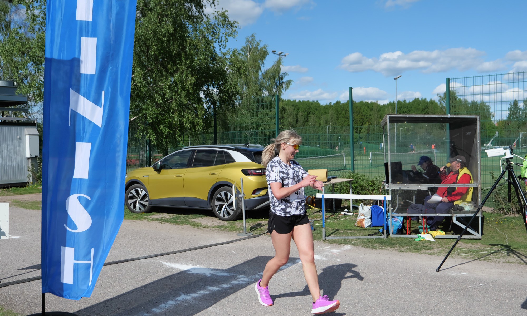 nainen juoksee maaliin maratonilla ja sammuttaa urheilukellonsa