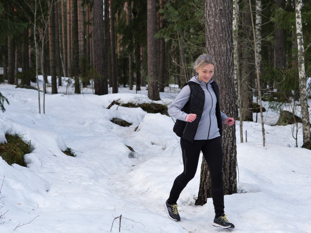nainen juoksee talvisessa metsassa
